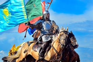2017 год. Фотография сделана во время байги в рамках Дней культуры Атырауской области. На фотографии представлен батыр, который, держа Флаг Казахстана в руке, грациозно мчится вперед.